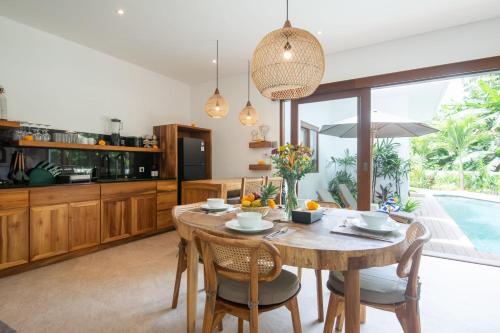 a kitchen and dining room with a wooden table and chairs at Villa Jacelyne - Tropical 2BR Villa with Private Pool in Canggu in Dalung