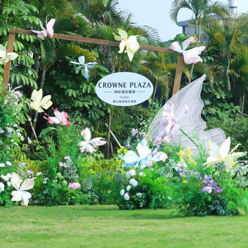 a sign in a garden with flowers and an umbrella at Crowne Plaza Foshan by IHG in Foshan