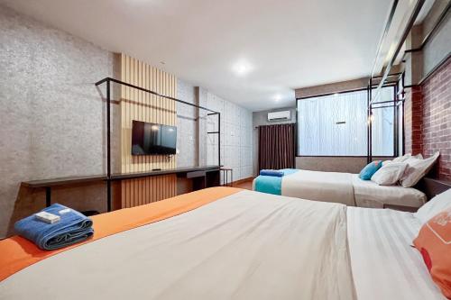 a hotel room with two beds and a tv at SANS Vibes Millenium Inn Medan in Pulauberayan