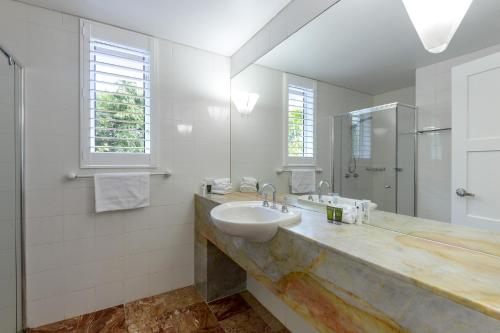 a white bathroom with a sink and a mirror at Balboa Apartments in Port Douglas
