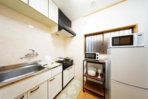 a small kitchen with a sink and a refrigerator at 10 minutes by train to Nagoya Station! Kominka guest house in Nagoya