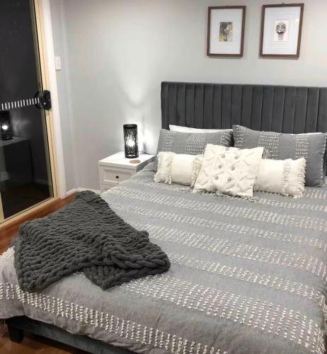 a bed with a gray blanket and pillows on it at Dees Rear Studio Room in Hazelbrook
