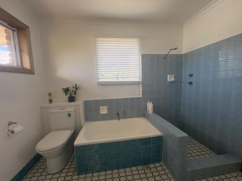 a bathroom with a tub and a toilet and a sink at Emerald Break- The Perfect Coastal Escape in Emerald Beach