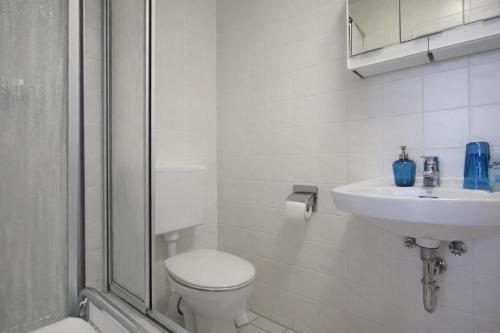 a white bathroom with a toilet and a sink at Haus Wilbrand Ferienzimmer 2 in Warnemünde
