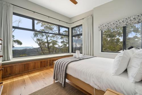 a bedroom with a large bed and large windows at Sunset Retreat in Mount Victoria