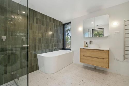 a bathroom with a tub and a sink and a mirror at Sunset Retreat in Mount Victoria