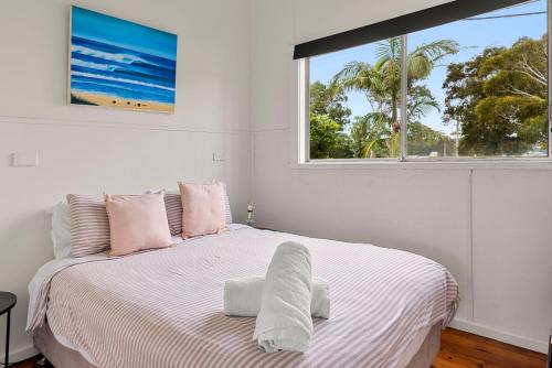 a white bedroom with a large bed with a window at Bluetongue at Culburra I Pet Friendly 4 Mins to Beach in Culburra Beach