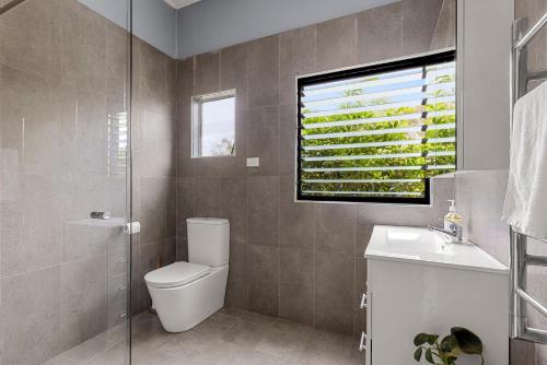 a bathroom with a toilet and a sink and a window at Bluetongue at Culburra I Pet Friendly 4 Mins to Beach in Culburra Beach