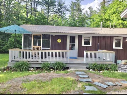 a small house with a porch and an umbrella at WILDFLOWER CABINS LIMIT 6 villa in Naples