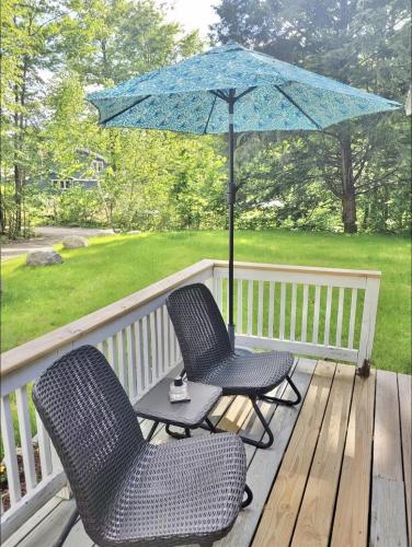 two chairs and a table with an umbrella on a deck at WILDFLOWER CABINS LIMIT 6 villa in Naples