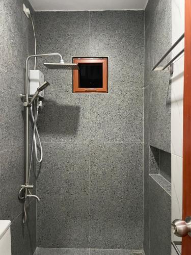 a bathroom with a shower with a tv on the wall at Norwil Manor Tagaytay in Tagaytay