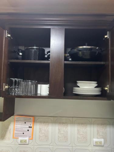 a kitchen cabinet with plates and pots and pans at Villa Arenal Volcano & Privade pool in Fortuna