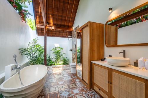 a bathroom with a large tub and a sink at Villa Apuh Rose in Ubud