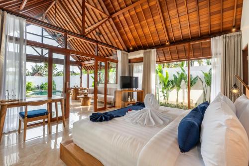 a bedroom with a large bed in a room with windows at Villa Apuh Rose in Ubud
