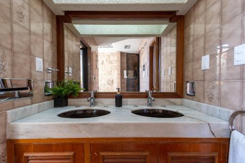 a bathroom with two sinks and a large mirror at Chapalita Grand House in Guadalajara