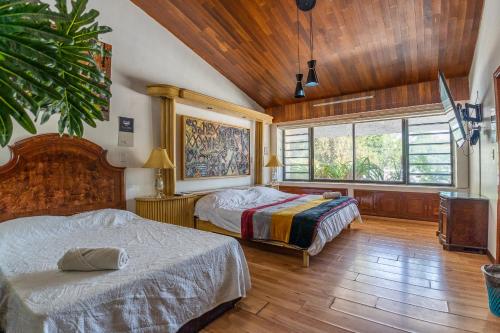 two beds in a room with wooden ceilings and wood floors at Chapalita Grand House in Guadalajara