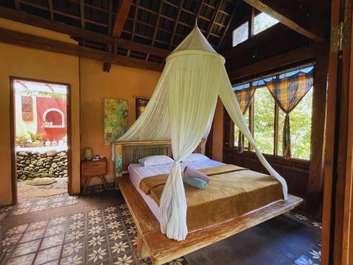 a bedroom with a bed with a mosquito net at duegoal farmhouse in Jatiluwih