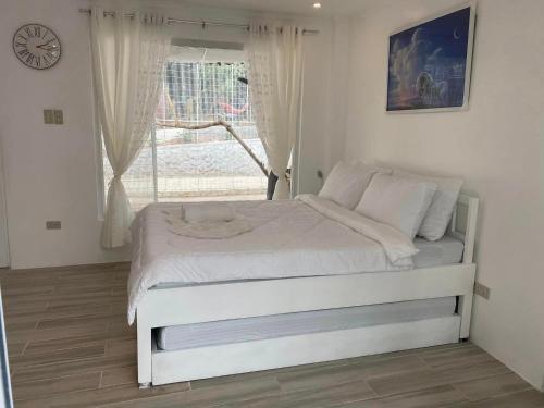 a white bed in a room with a window at Zoobic Glampz in Subic