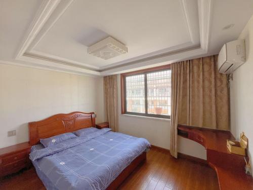 a bedroom with a bed with a blue comforter and a window at 青云小栈 in Shaoxing