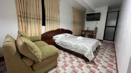 a bedroom with a bed and a couch and a chair at CATTLEYA Casa Hospedaje in Nueva Cajamarca