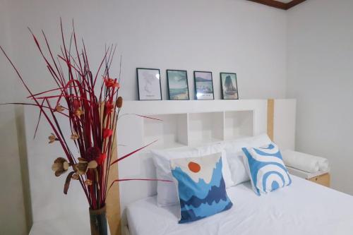 a bedroom with a white bed and a vase with flowers at Sampheng House in Bangkok
