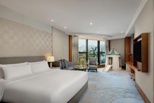 a bedroom with a bed and a living room at Kerry Hotel Hong Kong by Shangri-la in Hong Kong