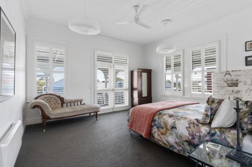 a bedroom with a bed and a chair and windows at Altitude Apartment in Martinborough