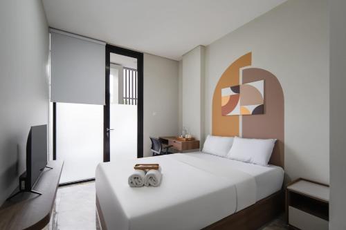 a bedroom with a large white bed with two engagement rings at Cove Casa Dyna in Jakarta