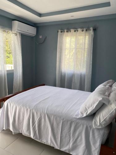 a bedroom with a bed with white sheets and a window at Anne's Emerald Tranquility Villas in Laborie