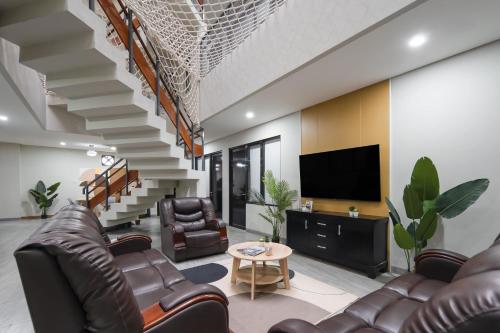 a living room with leather furniture and a tv at Cove Casa Dyna in Jakarta