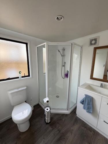 a bathroom with a toilet and a shower and a sink at Sailrock Studio in Mangawhai