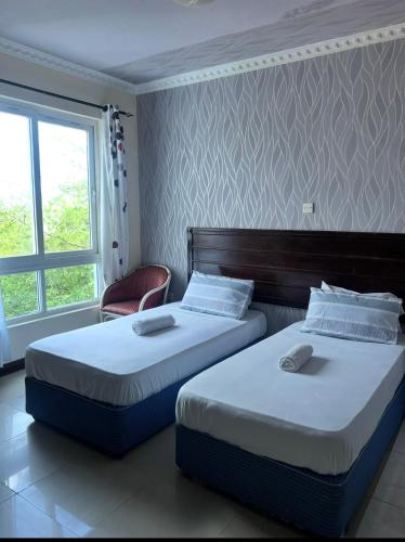 two twin beds in a room with a window at Sunrise-Nyali, Mombasa in Nyali
