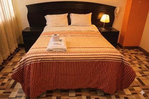 a hotel room with a bed with two towels on it at Hotel Bartol in Huancayo