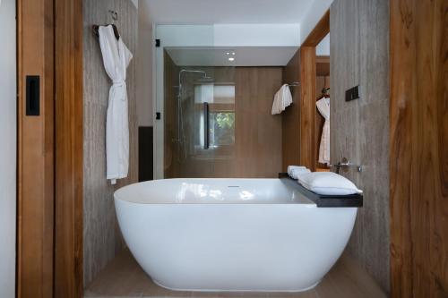 a white bath tub in a bathroom with a mirror at Rama Beach Resort and Villas in Kuta