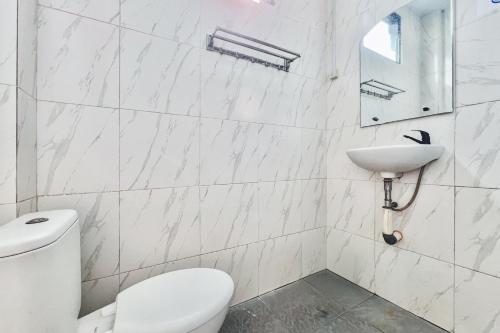 a white bathroom with a toilet and a sink at SANS Vibes Millenium Inn Medan in Pulauberayan