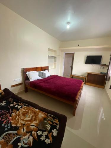 a bedroom with two beds and a tv on the wall at Sky High Villa - Ooty in Ooty