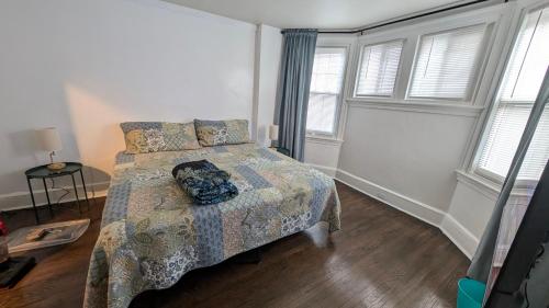 a bedroom with a bed with a comforter and windows at Rooftop GreeneHouse Suite in Philadelphia