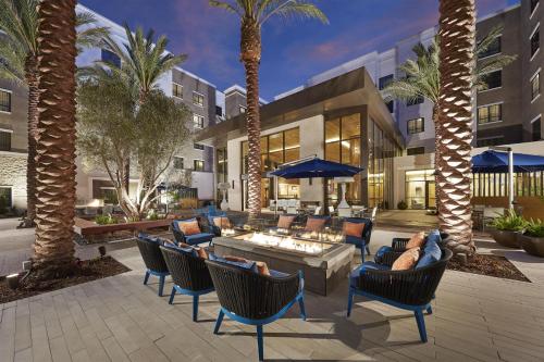 a patio with chairs and tables and palm trees at Homewood Suites by Hilton San Diego Hotel Circle/SeaWorld Area in San Diego