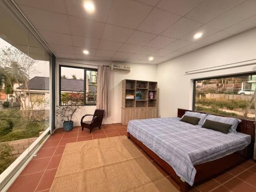 a bedroom with a bed and a large window at Peaceful Hilltop Duplex Central Phu Quoc in Phú Quốc
