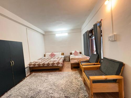 a room with two beds and a chair and a rug at Divine Homestay Dirang in Dirang Dzong