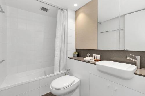 a white bathroom with a toilet and a sink at Squatters Run 26 in Thredbo