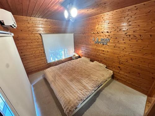 a bedroom with a bed in a wooden wall at Mori Vila Aso in Takamori