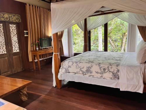 a bedroom with a canopy bed and a window at Mi Casa - The gem of Ijen in Banyuwangi
