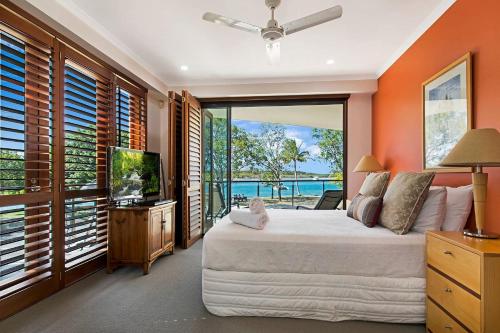 a bedroom with a large bed and a tv and windows at Nouvelle in Noosaville