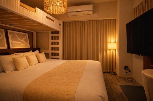 a hotel room with a large bed and a television at 国際通り徒歩5分 ホテルライクコンドミニアム 自転車3台無料 だるまマンション903 in Naha