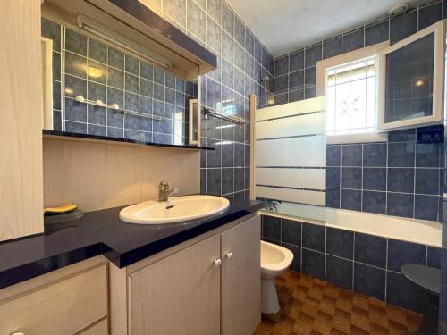 a blue tiled bathroom with a sink and a toilet at Sarthou in Espéchède