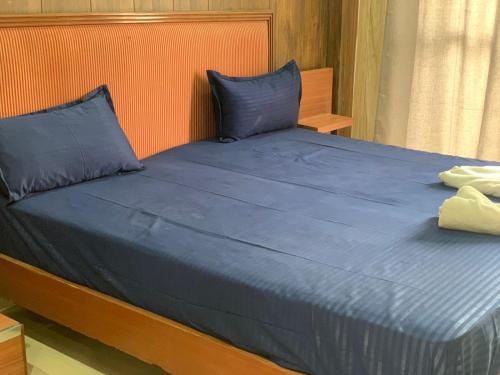a bed with blue pillows and a blue sheet at Nirvana Maldevta in Dehradun