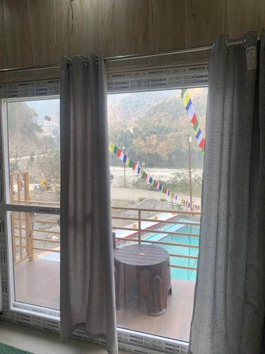 a window with a table and a view of a balcony at Nirvana Maldevta in Dehradun