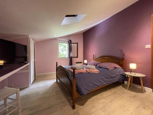 a bedroom with a bed with purple walls and a tv at Chez garcia in Urrugne