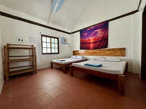 a room with two beds and a painting on the wall at North Shore Surf Camp in Baler